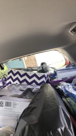 A car backseat packed with various boxes and creates to where rear window barely visible.