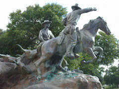 A bronze statue of men wearing cowboy hats and riding on horseback.