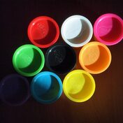 The tops of Play-Doh containers in many colors sit on a table.