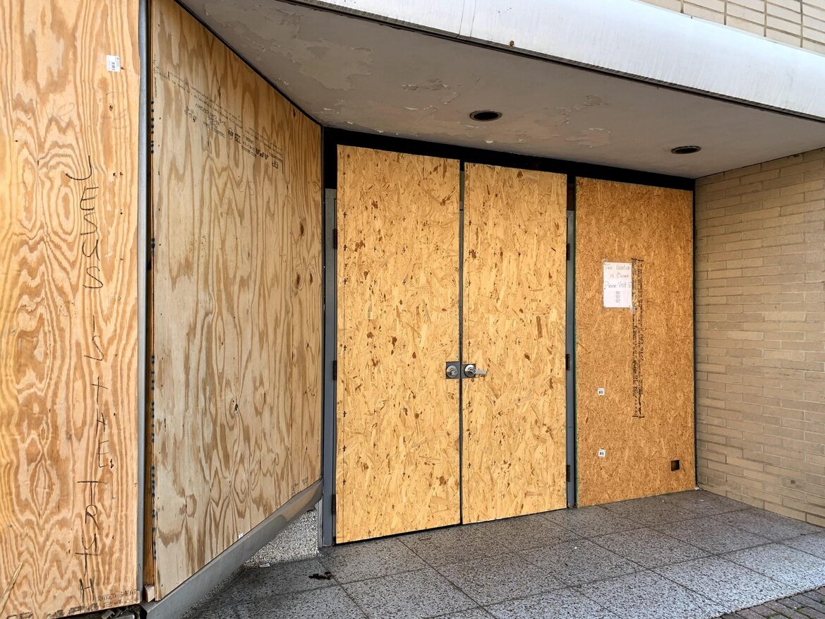 A door and its surrounding panels are covered in plywood.